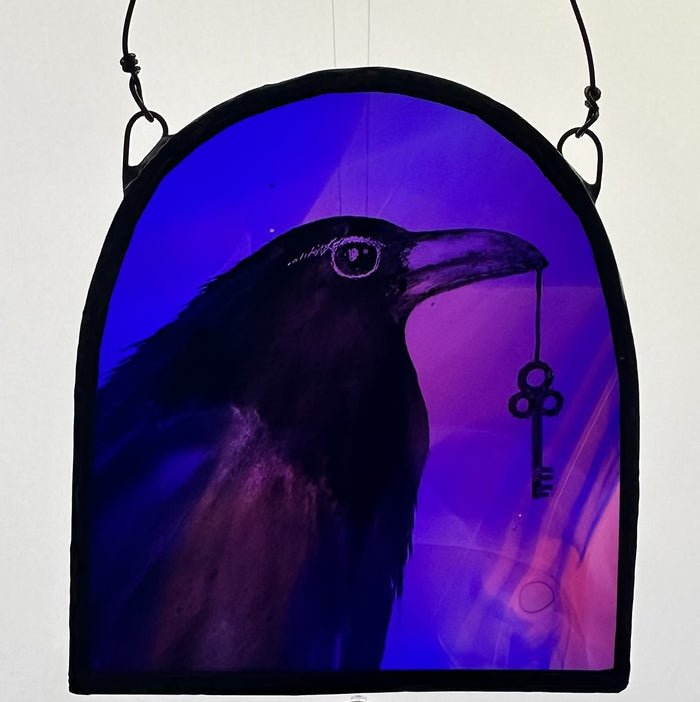 Decorative piece with a silhouette of a raven holding a key against a purple background