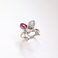 Silver ring with pink and rainbow moonstone gemstones on a white background