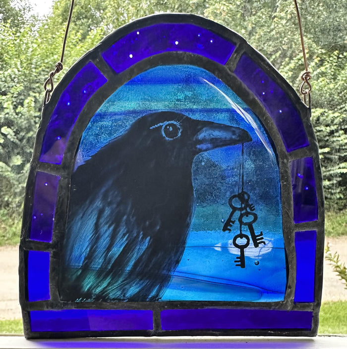 Stained glass panel with a crow and key design, set against a blue background.