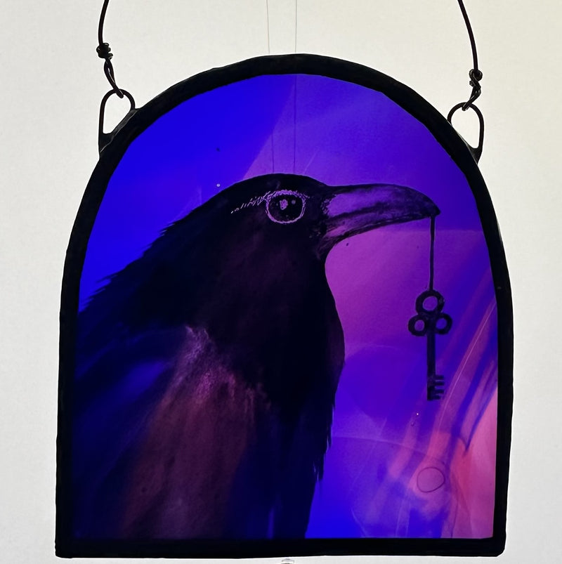 Decorative piece with a silhouette of a raven holding a key against a purple background
