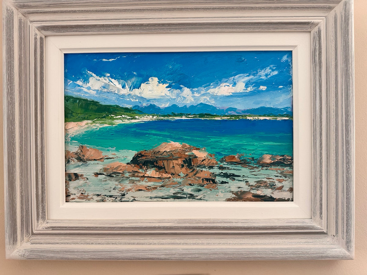Framed painting of a coastal scene with rocks, water, and sky.