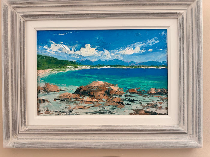 Framed painting of a coastal scene with rocks, water, and sky.